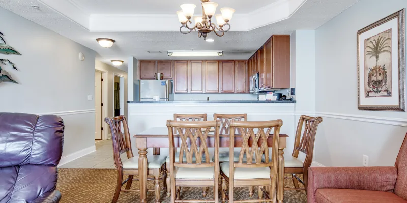 A wide view of a living room and kitchen area with a dining table, sofa, and kitchenette.
