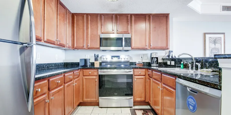 A kitchen with stainless steel appliances, wood cabinets, and granite countertops.