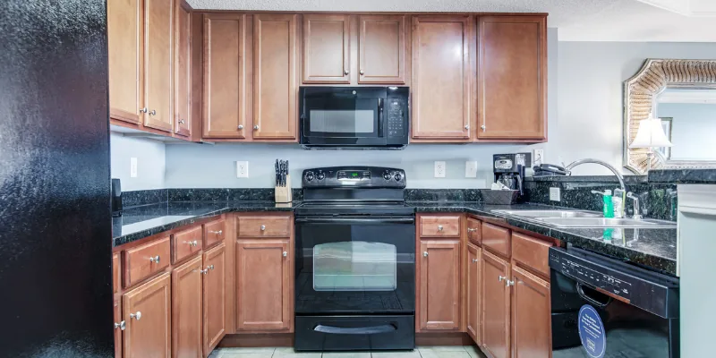 A kitchen with wooden cabinets, black appliances, and granite countertops.