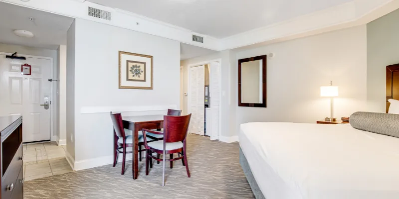 A hotel room with a bed, dining table, and door